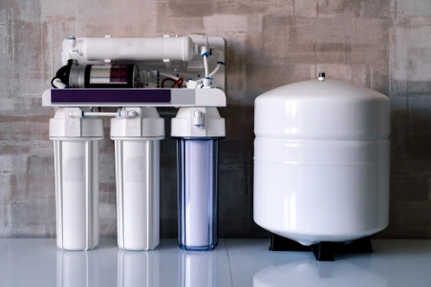 Placard ouvert révélant un système de filtration d'eau domestique installé sous évier