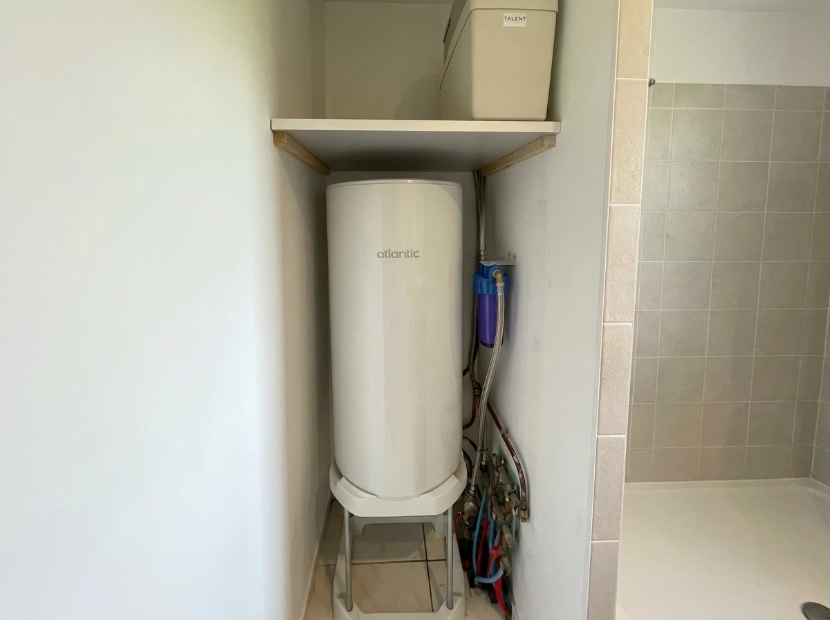 Une main installe un filtre à eau domestique sur un robinet de cuisine en inox