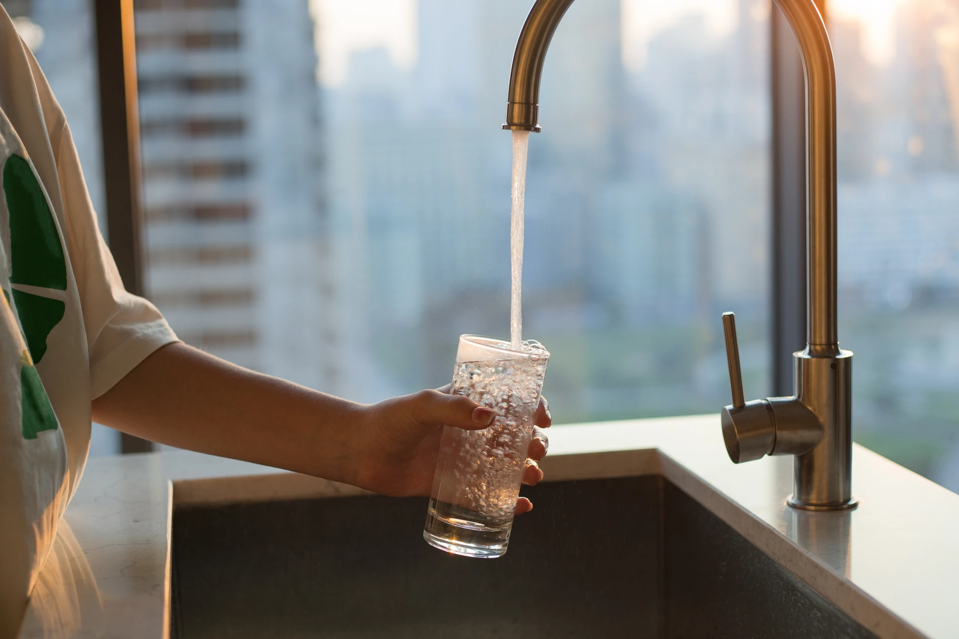 Intérieur carrelé blanc, main masculine manipulant un système de filtration d'eau