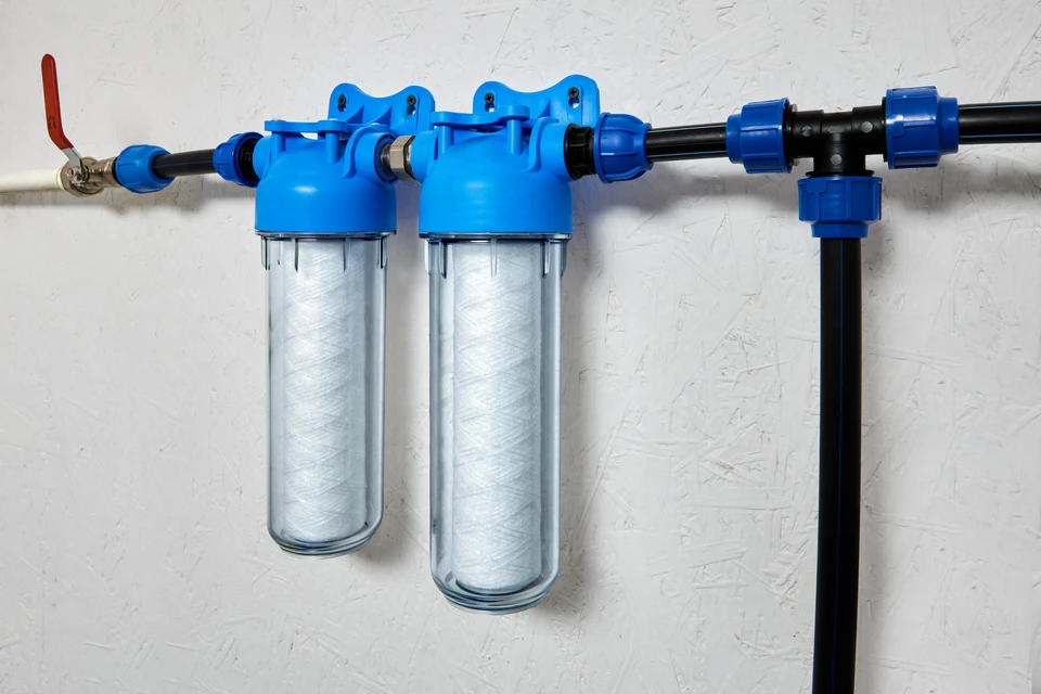 Technicien en combinaison bleue installant un système de filtration d'eau à osmose inverse sous un évier de cuisine