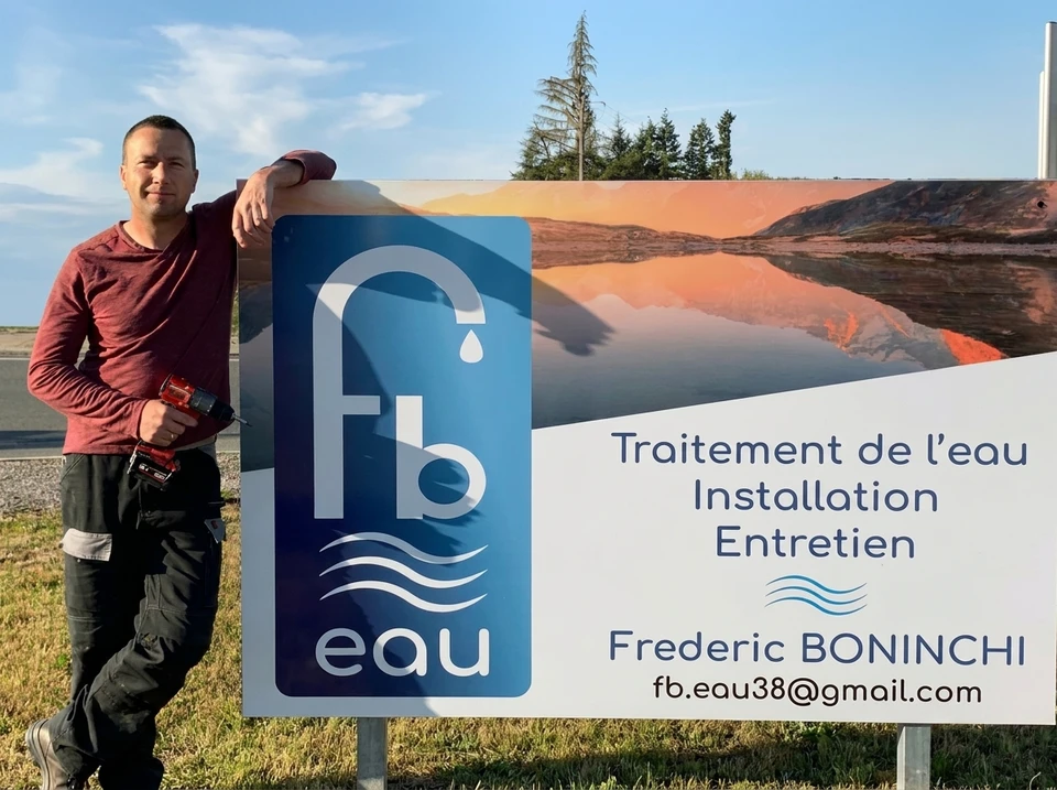 Technicien en combinaison bleue installant un système de filtration d'eau sous évier de cuisine moderne