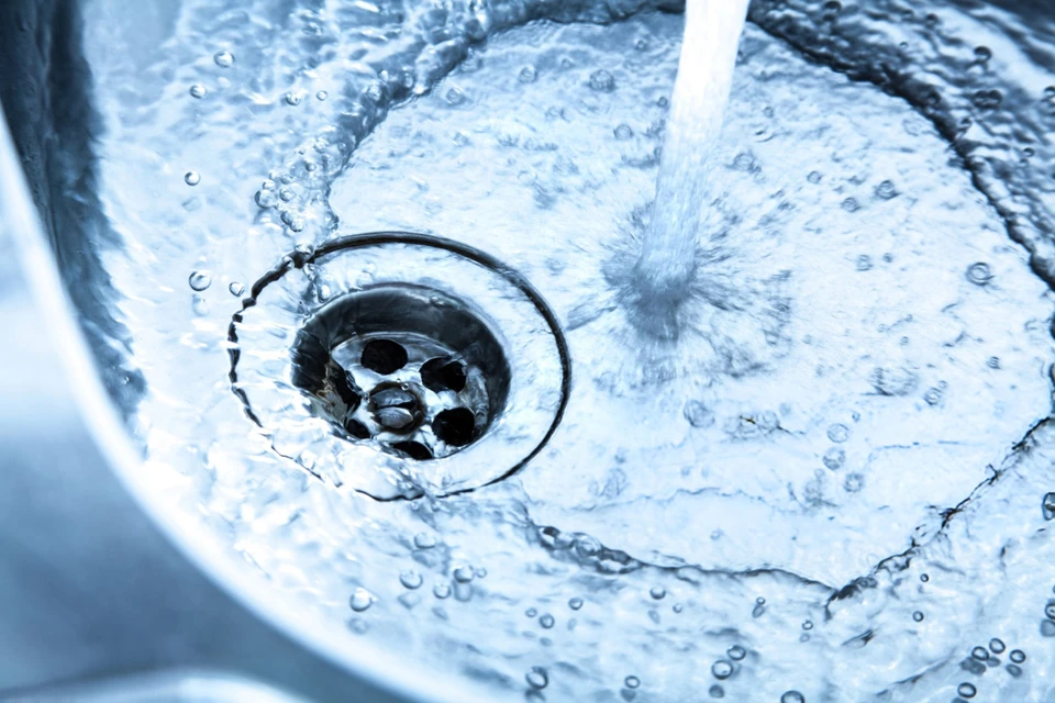 Intérieur carrelé blanc, main masculine manipulant un système de filtration d'eau
